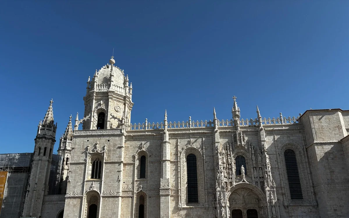 La fachada de piedra clara tallada del Monasterio de los Jerónimos bajo un cielo azul