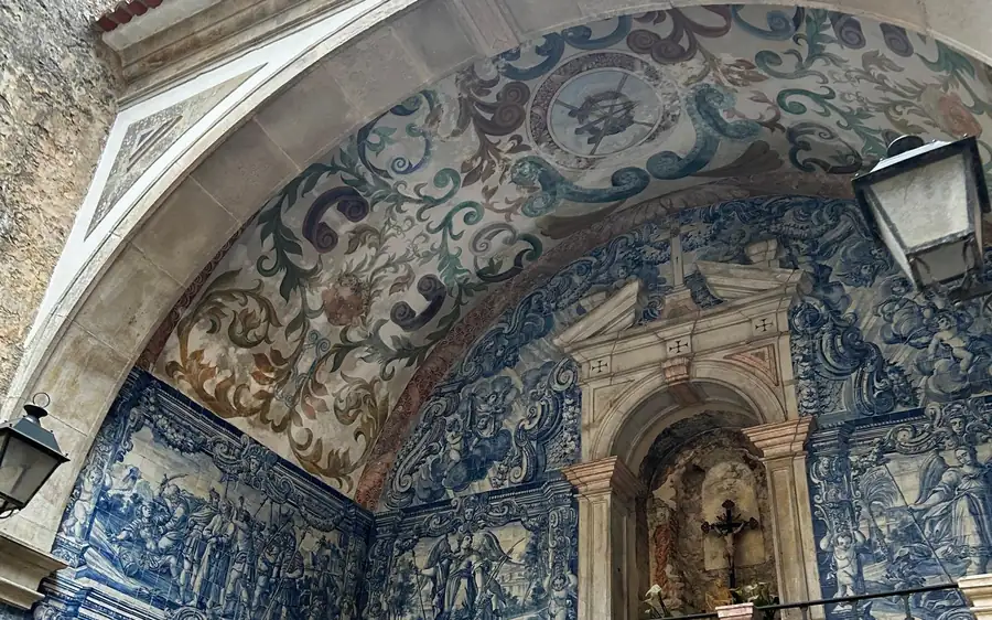 Blaue und weiße Fliesen in einem steinernen Torbogen mit einem kleinen Altar