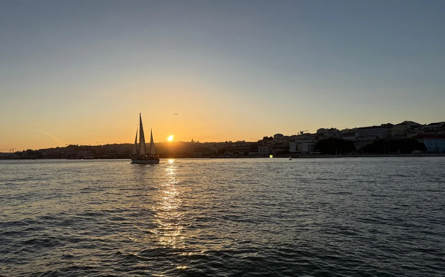 Ein Segelboot auf dem Fluss mit tiefer Sonne über dem anderen Ufer